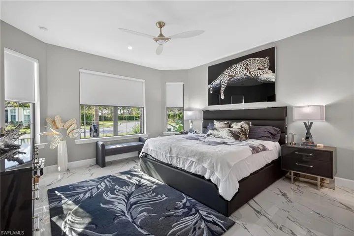 Bedroom featuring a ceiling fan and marble finish floors