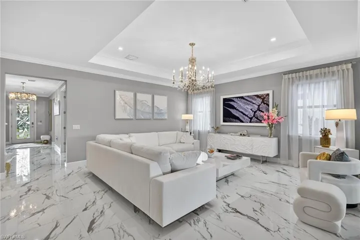 Living area featuring a chandelier, crown molding, healthy amount of natural light, light marble finish flooring, and recessed lighting