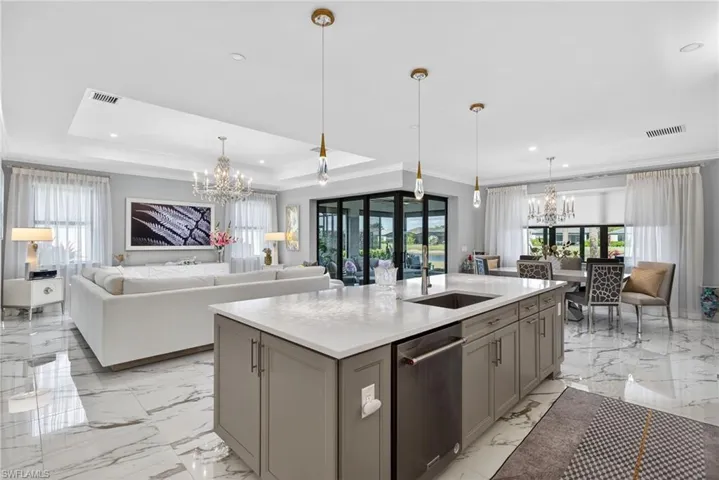 Kitchen featuring a chandelier, open floor plan, ornamental molding, dishwasher, and a kitchen island with sink