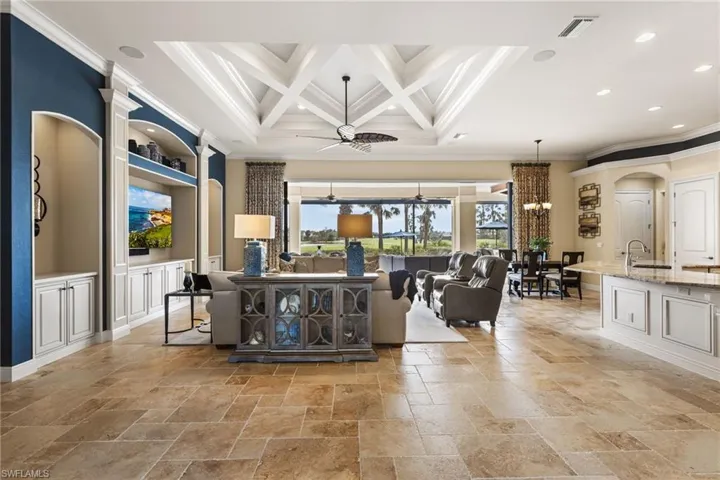 Living room featuring ornamental molding, coffered ceiling, ceiling fan with notable chandelier, and beam ceiling
