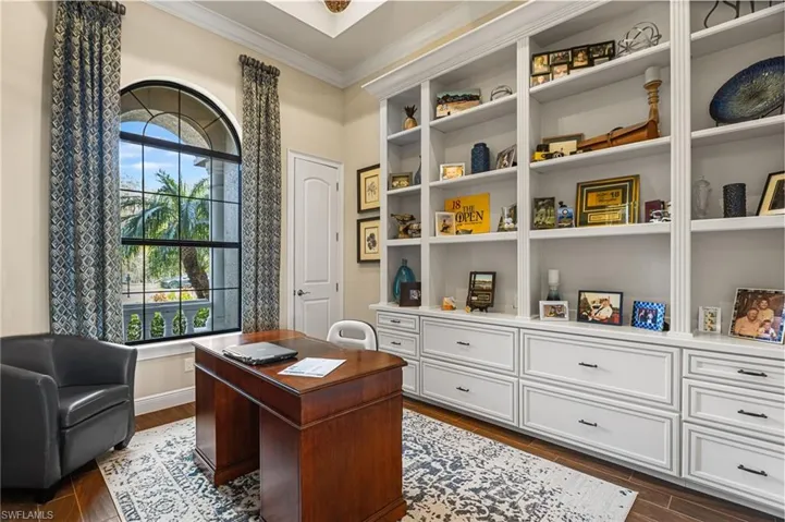 Home office featuring dark wood-type flooring, ornamental molding, and plenty of natural light