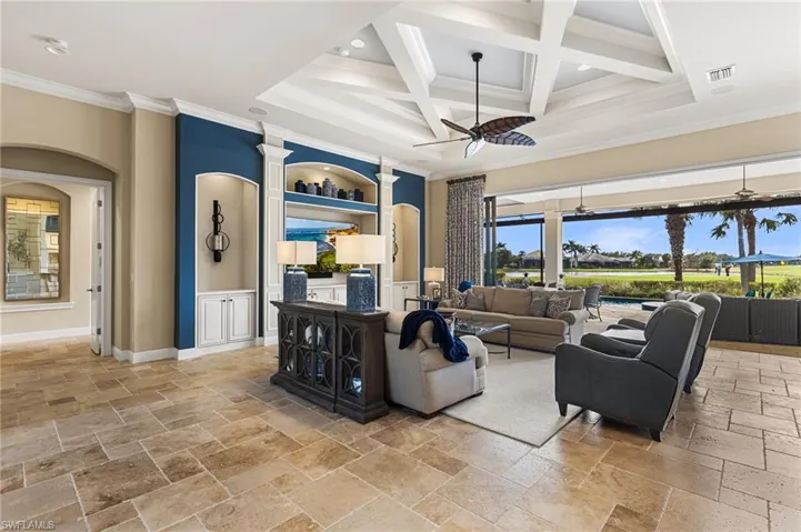 Living room with coffered ceiling, crown molding, built in features, beamed ceiling, and ceiling fan