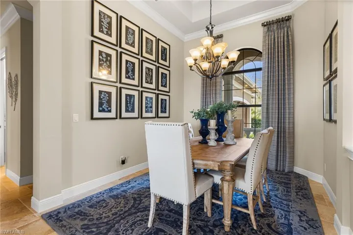 Dining room featuring an inviting chandelier, a tray ceiling, and crown molding