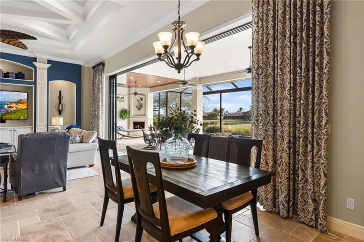 Dining area with crown molding, coffered ceiling, ceiling fan with notable chandelier, and beamed ceiling