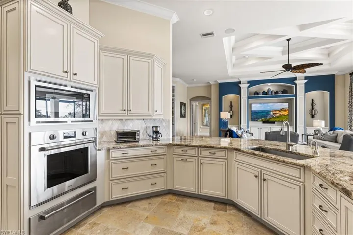 Kitchen featuring coffered ceiling, sink, ornamental molding, appliances with stainless steel finishes, and beam ceiling