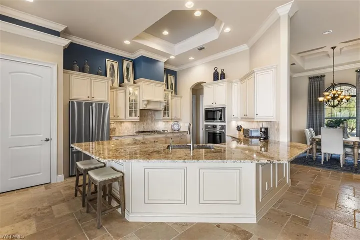 Kitchen with sink, appliances with stainless steel finishes, backsplash, a tray ceiling, and a kitchen bar