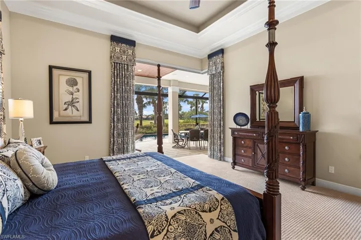 Bedroom featuring a tray ceiling, crown molding, access to outside, and carpet