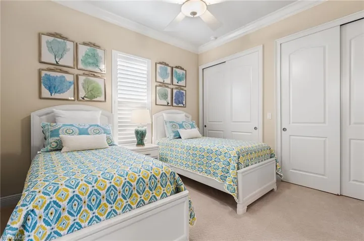 Carpeted bedroom with ceiling fan and ornamental molding