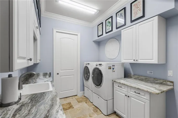 Laundry area featuring cabinets, ornamental molding, separate washer and dryer, and sink