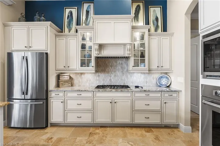 Kitchen with tasteful backsplash, light stone countertops, and stainless steel appliances