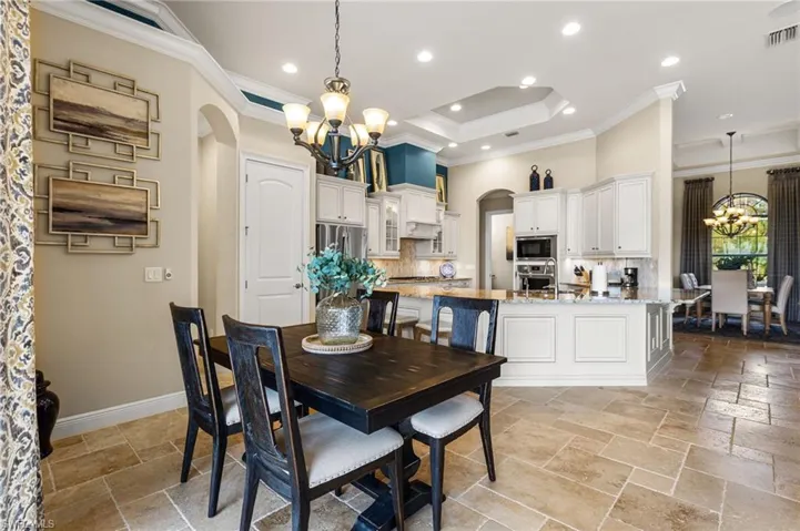 Dining room featuring an inviting chandelier, crown molding, and a raised ceiling