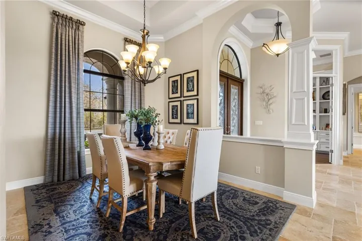 Dining room with an inviting chandelier, a towering ceiling, and ornamental molding