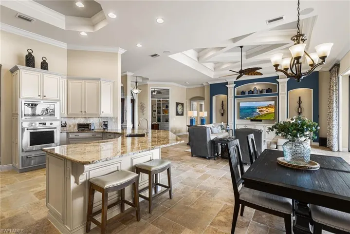 Kitchen featuring built in microwave, oven, a kitchen breakfast bar, light stone counters, and crown molding