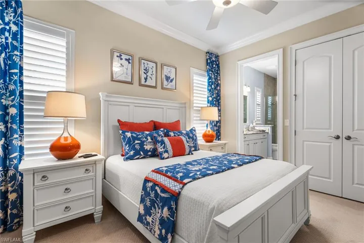 Carpeted bedroom featuring multiple windows, ensuite bath, ceiling fan, and a closet