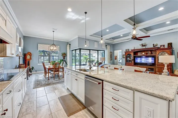 Kitchen with dishwasher, white cabinetry, hanging light fixtures, and a large island with sink