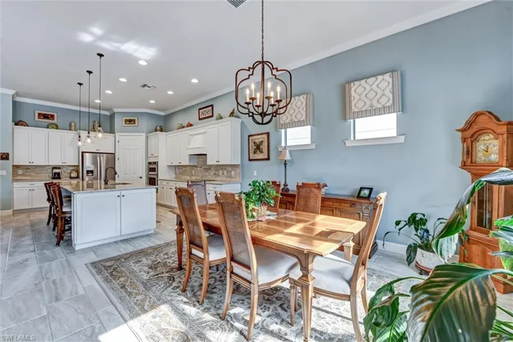 Dining space featuring light tile patterned flooring, sink, an inviting chandelier, and crown molding