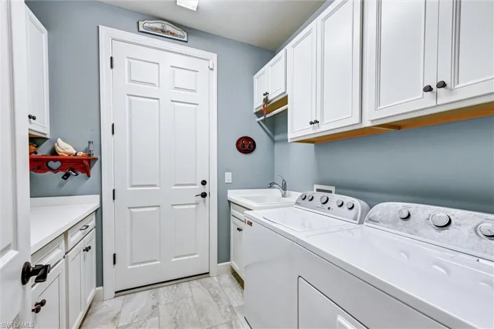 Clothes washing area featuring cabinets, washing machine and dryer, and sink