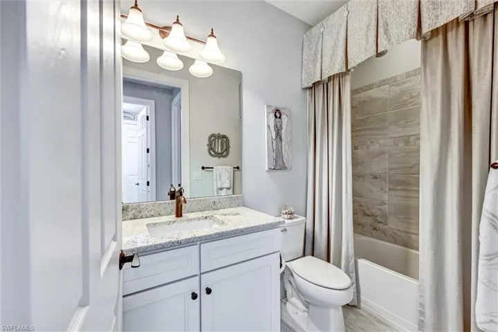 Full bathroom featuring shower / tub combo with curtain, vanity, and toilet