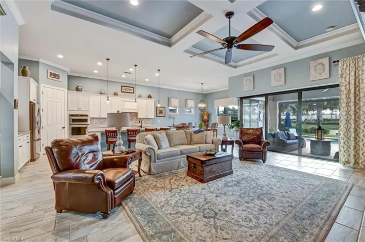 Living room featuring a towering ceiling, crown molding, coffered ceiling, beamed ceiling, and ceiling fan