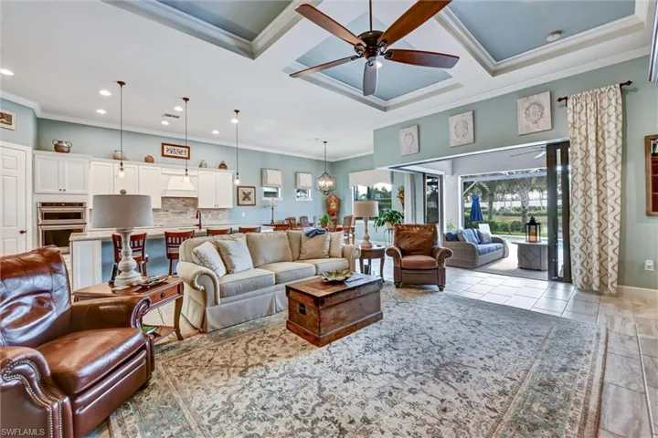Tiled living room with ceiling fan, crown molding, and coffered ceiling