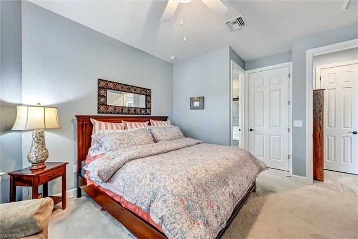 Bedroom with ensuite bathroom, ceiling fan, and light carpet