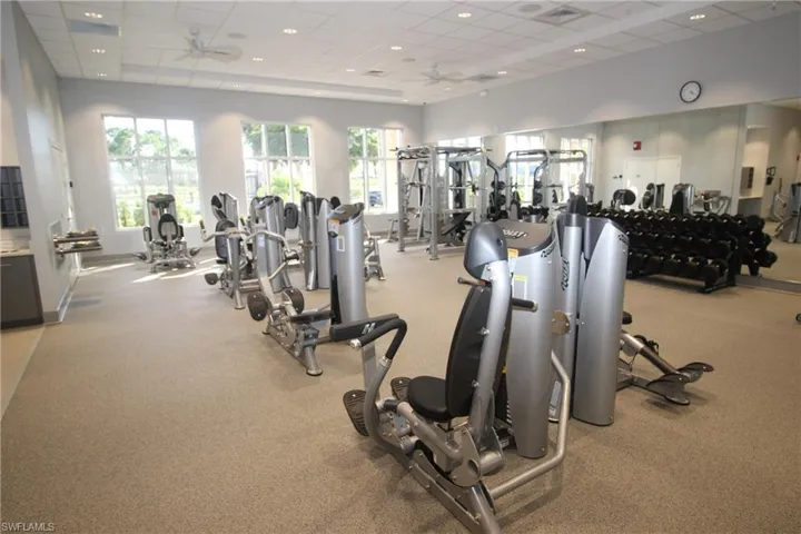 Exercise room with a paneled ceiling, ceiling fan, and a healthy amount of sunlight