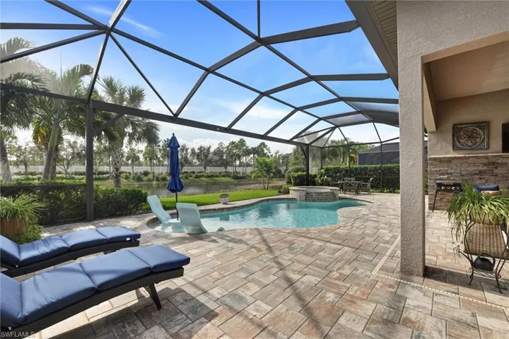 View of pool featuring glass enclosure, an in ground hot tub, and a patio area
