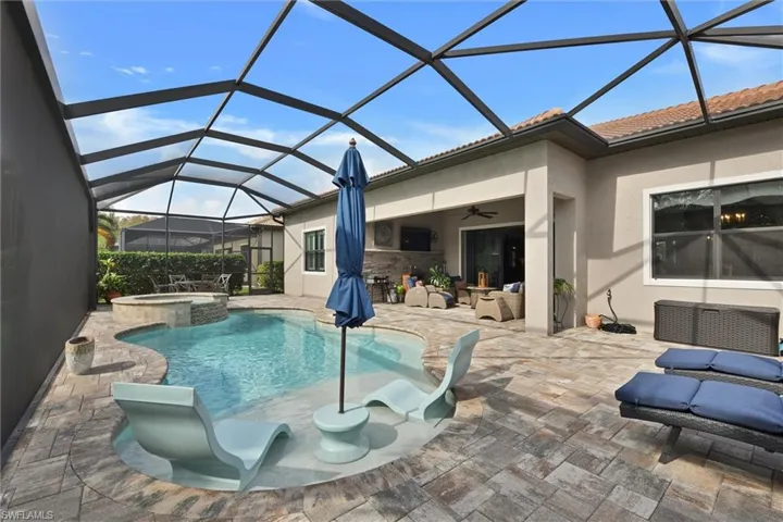 View of swimming pool with glass enclosure, ceiling fan, a patio, and an in ground hot tub