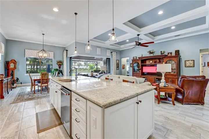 Kitchen with white cabinets, light stone countertops, sink, and an island with sink