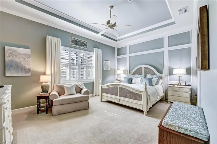 Bedroom featuring ornamental molding, light colored carpet, ceiling fan, and a raised ceiling