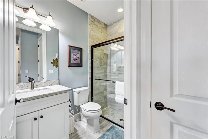 Bathroom with an enclosed shower, wood-type flooring, toilet, and vanity