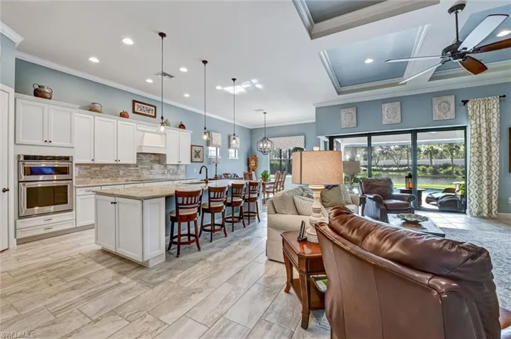 Living room featuring ornamental molding, ceiling fan, sink, and coffered ceiling