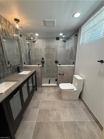 Full bath with double vanity, a stall shower, light tile patterned flooring, and recessed lighting