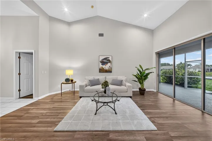 Living area opens through sliders to the screened lanai and a tranquil pond view beyond.