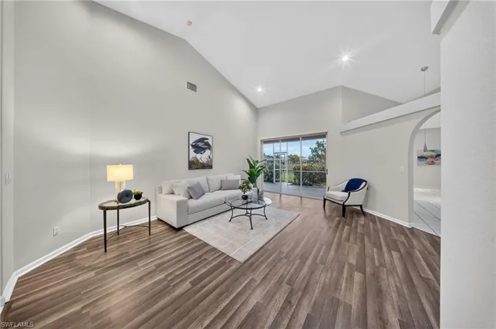 Formal living room with a wall of sliders to the backyard and pond, filled with afternoon light.