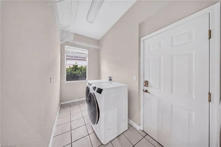 Interior laundry room with front-load washer, new utility tub and storage.