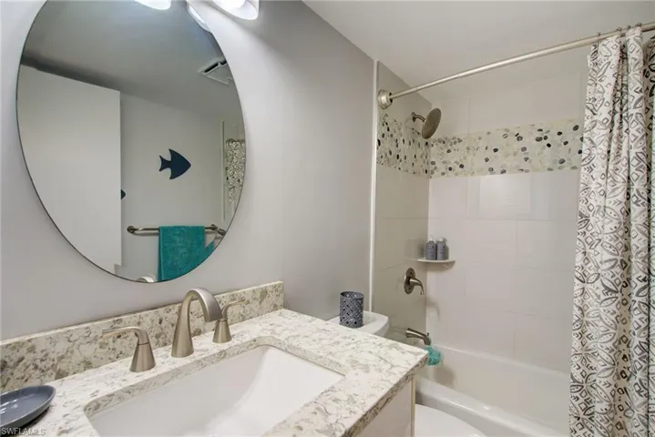 Bathroom featuring vanity and shower / bath combination with curtain