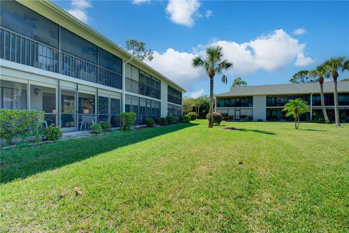 View of grassy yard with a sunroom and a balcony
