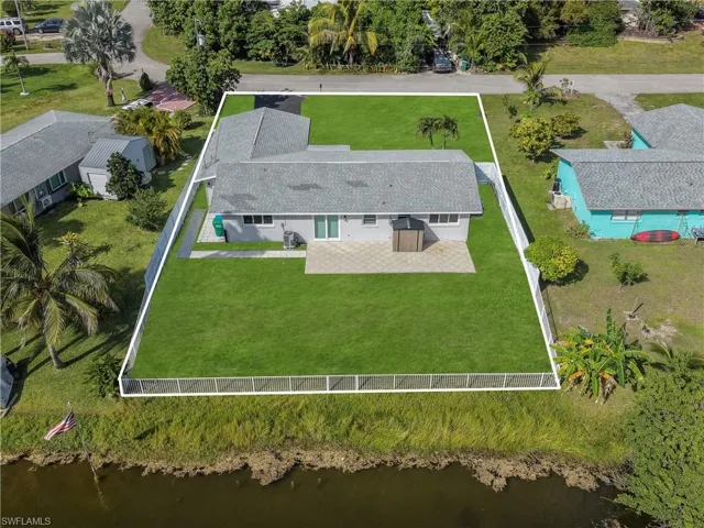 Fenced backyard featuring a paved patio, manicured lawn, and water frontage