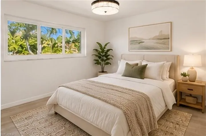 Neutral-toned room featuring wide-format horizontal sliding windows, wood-finish flooring, and a decorative circular flush-mount light fixture