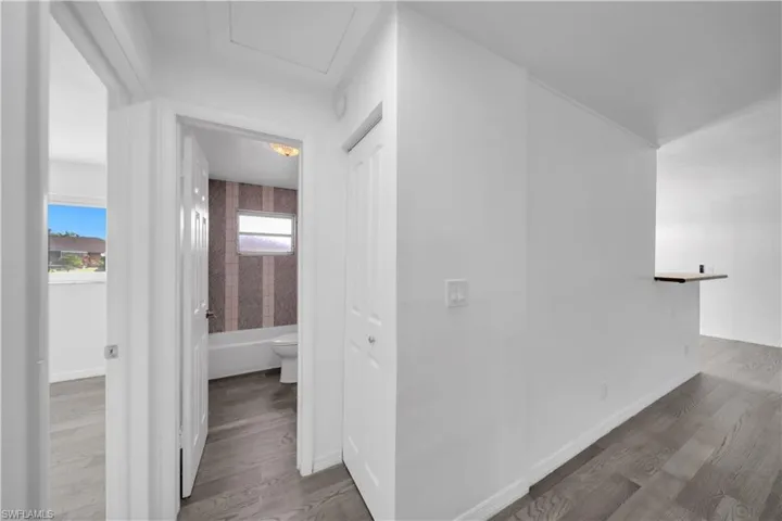 Wood-finish flooring throughout, interior doorway providing access to a bathroom, built-in closet storage, and a pass-through opening