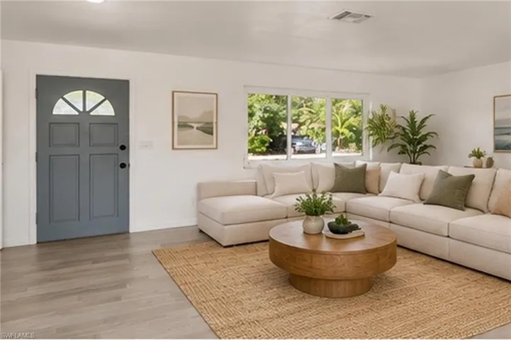Interior space featuring wood-finish flooring, a neutral color palette, and a multi-panel exterior entry door with an arched glass insert