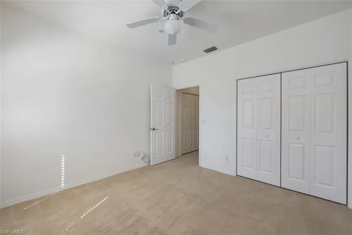 Unfurnished bedroom featuring light colored carpet, a ceiling fan, and a closet