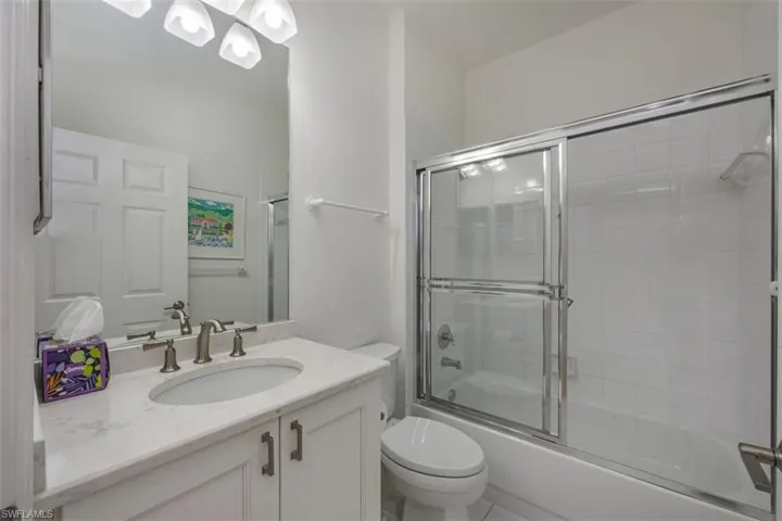 Bathroom featuring vanity, shower / bath combination with glass door, and a chandelier