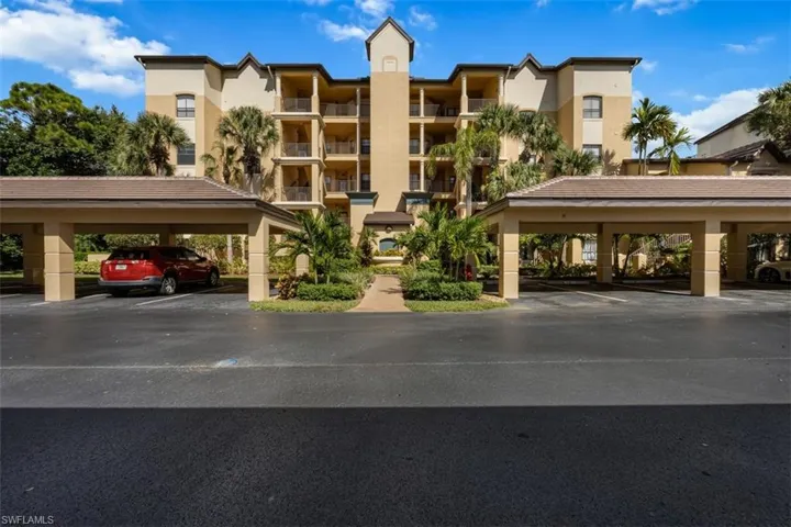 View of apartment building / complex featuring covered parking
