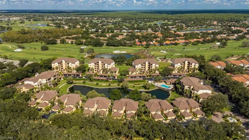 Aerial view of property and surrounding area with a local golf course, a large body of water, and nearby suburban area