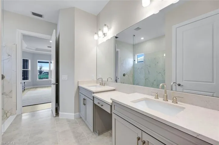 Bathroom featuring a marble finish shower, double vanity, healthy amount of natural light, and light tile patterned flooring
