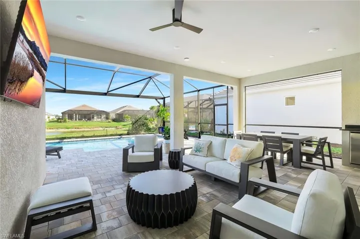 View of patio / terrace featuring a sunroom, outdoor lounge area, ceiling fan, an outdoor pool, and a lanai