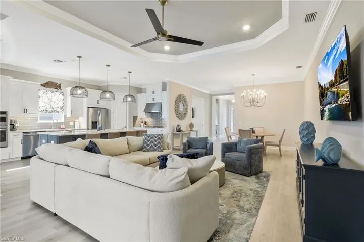 Living room featuring ceiling fan, crown molding, a chandelier, light wood finished floors, and recessed lighting