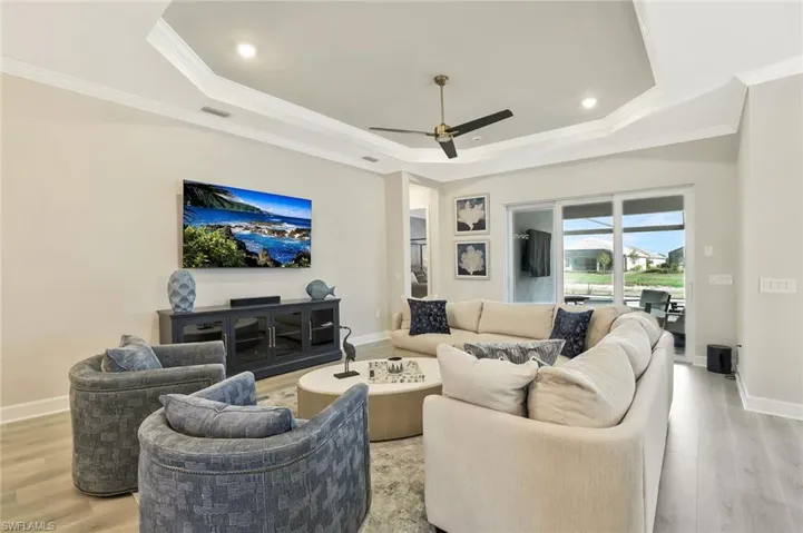 Living room featuring wood finished floors, ornamental molding, ceiling fan, recessed lighting, and a raised ceiling